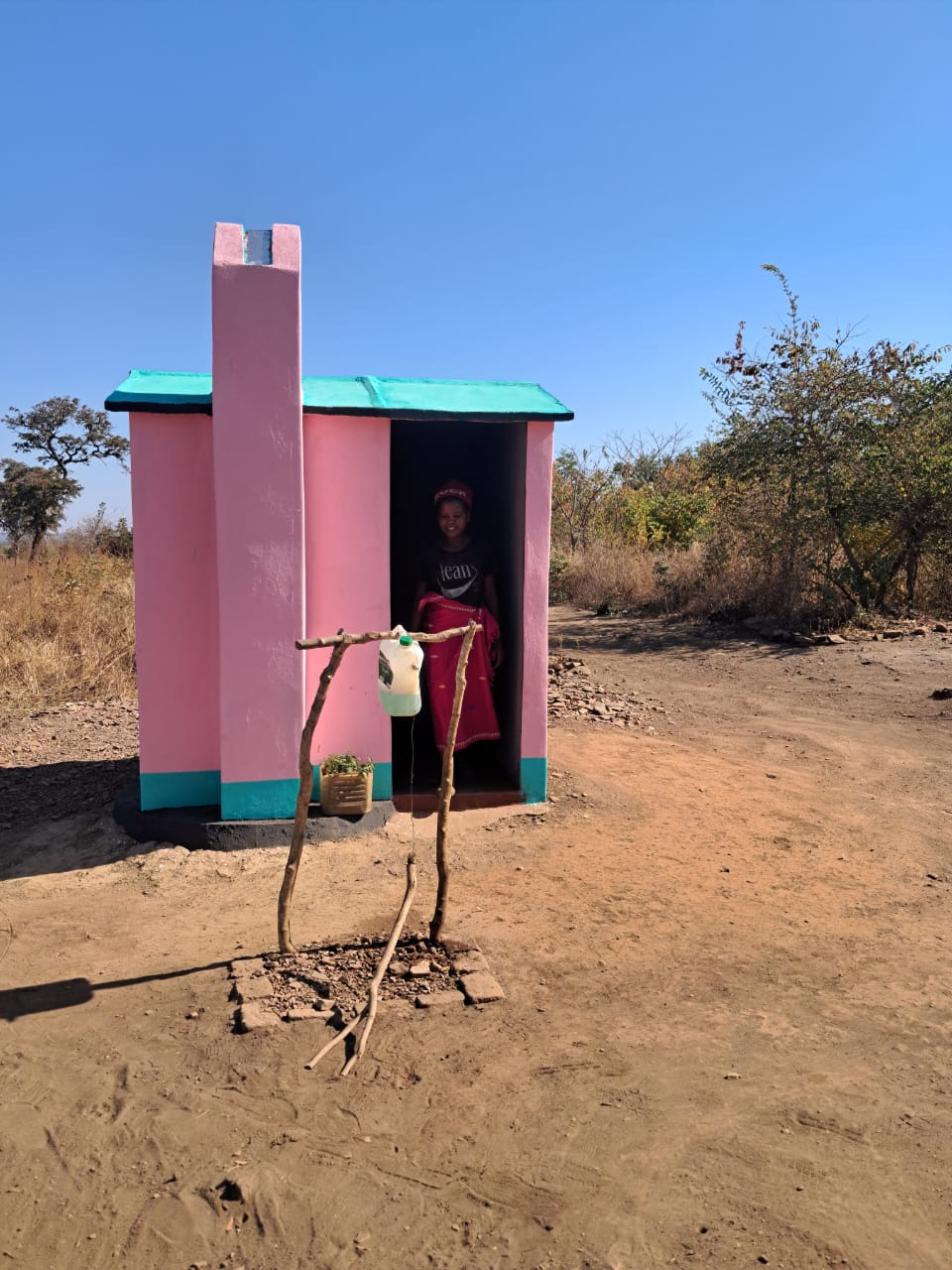Mwemba Village Six resident standing at a completed toilet with handwashing station