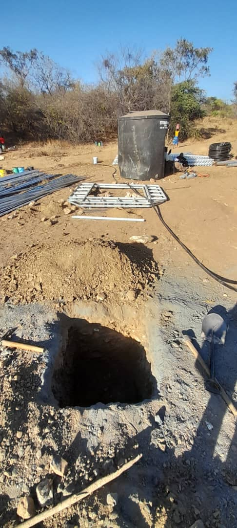 Excavated foundation, water storage tank and pipework at the piped water scheme construction site