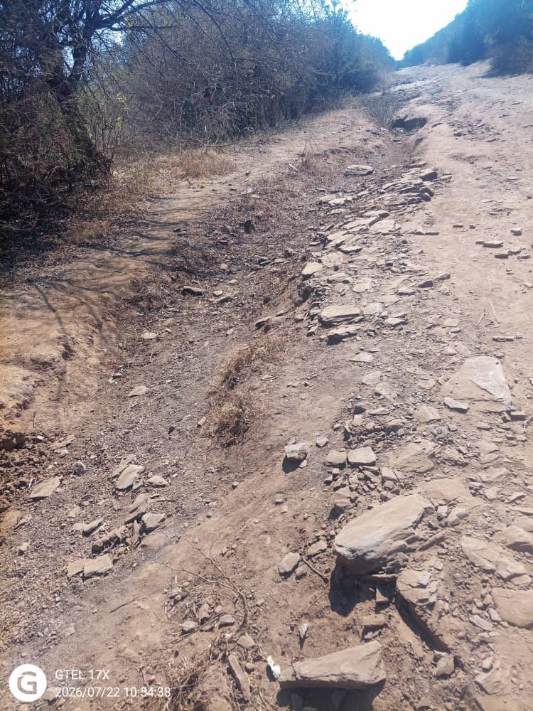 Ward 18 road before maintenance showing erosion, exposed rocks and an uneven track